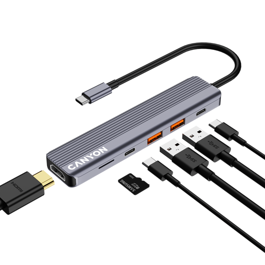 Szary hub USB-C z logo \'CANYON\', posiada kilka portów, w tym HDMI, USB i czytnik kart microSD. Obok znajdują się różne kable i karta microSD marki Samsung.