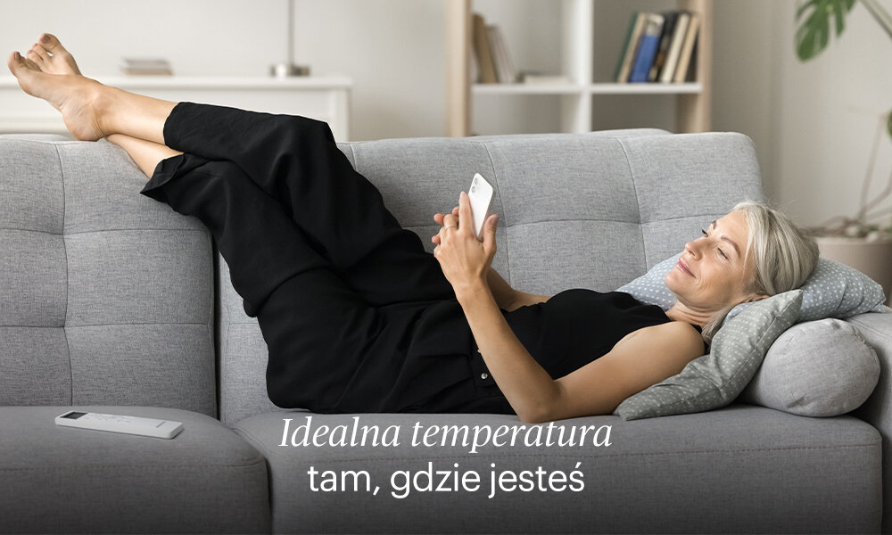 Klimatyzator Split, Pompa ciepła powietrze - powietrze GRUNDIG GEEPDE090 z usługą montażu Tam, gdzie jesteś Funkcja ZoneFollow zdjęcie lifestyle osoba leży na kanapie z telefonem