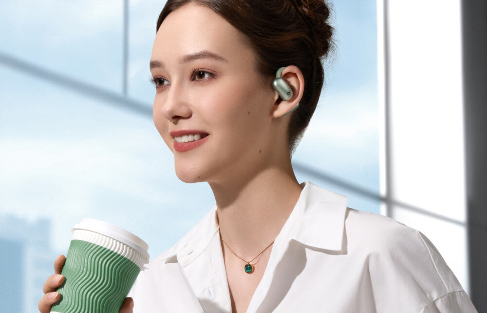 Słuchawki powietrzne SOUNDCORE AeroFit 2 lekkie douszne otwarta konstrukcja komfort noszenia, osoba trzymająca kubek w ręku z założonymi słuchawkami