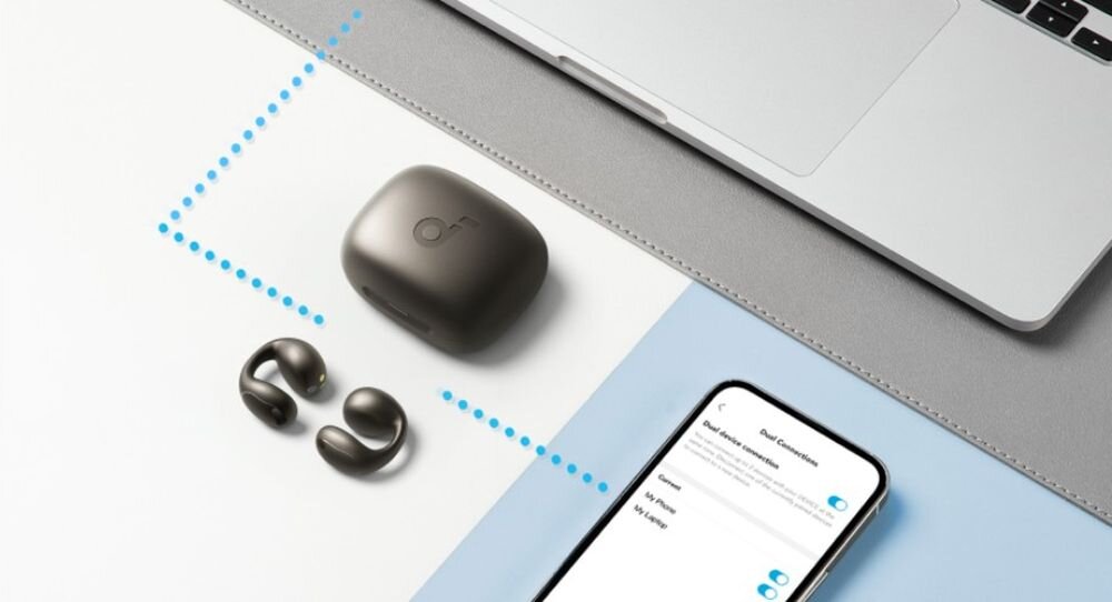 Słuchawki powietrzne SOUNDCORE C40I IPX4 wodoodporność trening spacery, słuchawki z etui ładującym leżąca na biurku obok smartfona oraz laptopa