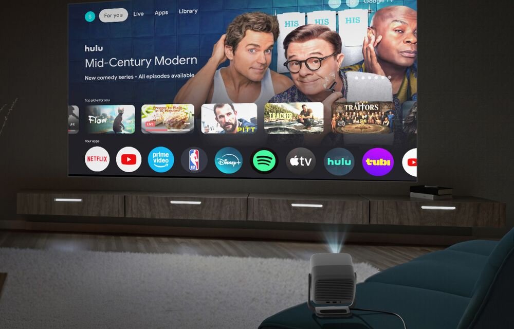 Na obrazie widać projektor wyświetlający interfejs telewizyjny z aplikacjami takimi jak Netflix, Prime Video, Disney+, Spotify, Apple TV, Hulu i YouTube. Na ekranie widoczny jest program \'Mid-Century Modern\' na platformie Hulu.