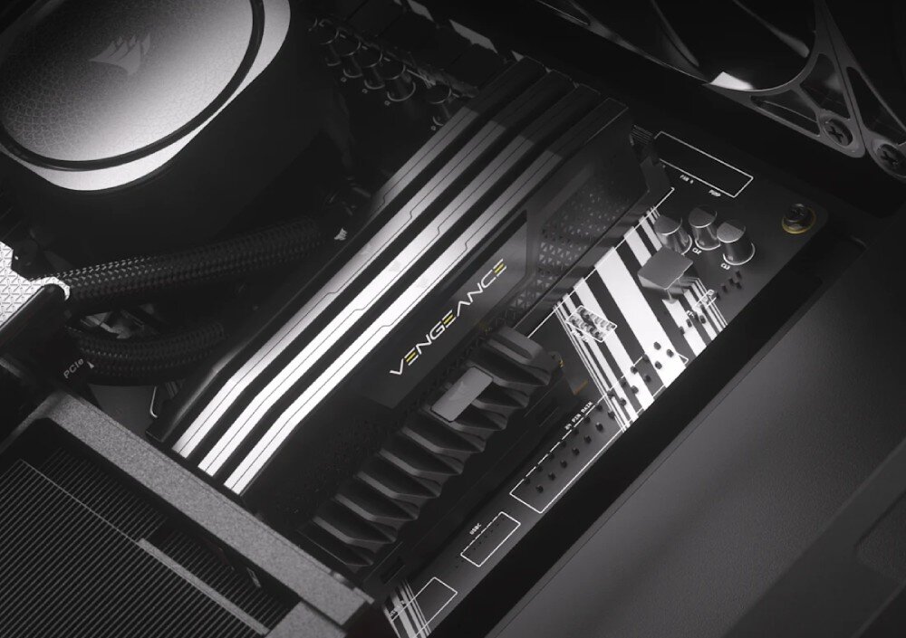 Zdjęcie przedstawia wnętrze komputera z widoczną pamięcią RAM z napisem \'VENGEANCE\' oraz fragmentem płyty głównej z elementami elektronicznymi. Na płycie głównej widoczne jest logo producenta w formie stylizowanego żagla.