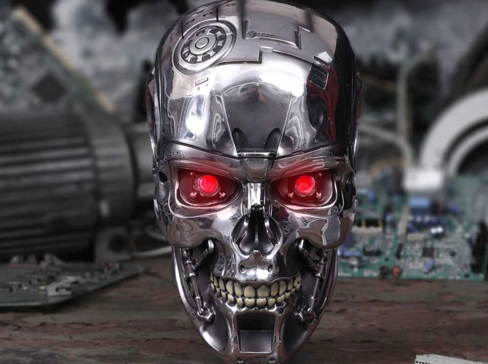 Metaliczna głowa robota z czerwonymi, świecącymi oczami i szczegółowymi elementami mechanicznymi. W tle widoczne są rozmyte elementy elektroniczne.