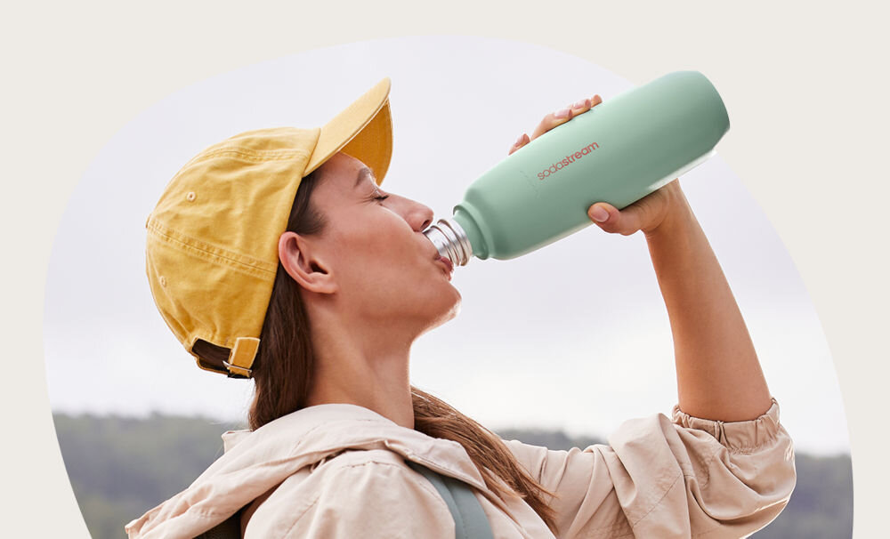 BUTELKA TERMICZNA SODASTREAM DO GAZOWANIA WODY MIĘTA 0.9L kobieta pije napój z butelki w kolorze miętowym żółta czapka jasne tło funkcjonalność stylowy design szczelna konstrukcja silikonowa uszczelka elastyczny pasek bez BPA z materiałów wolnych od bisfenoli Trwała i solidna z odpornej na uderzenia i korozję stali nierdzewnej 18/8 Łatwe czyszczenie do zmywarki