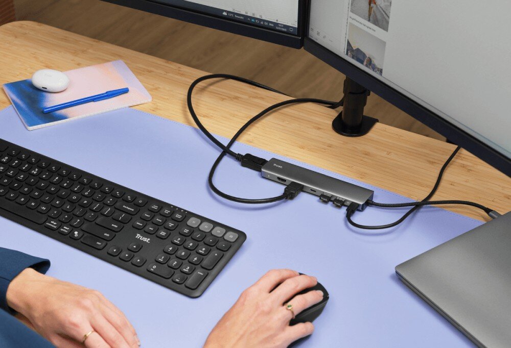 Hub TRUST Dalyx 25661 Kadr z góry na biurko pokazujący ręce osoby pracującej na klawiaturze i myszce podłączonych do laptopa przez wieloportowy hub