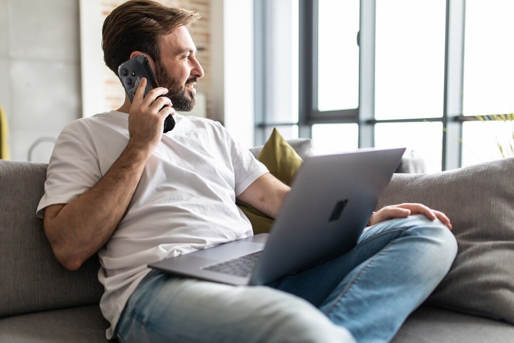 Smartfon OSCAL Marine 2 człowiek z laptopem na kanapie   