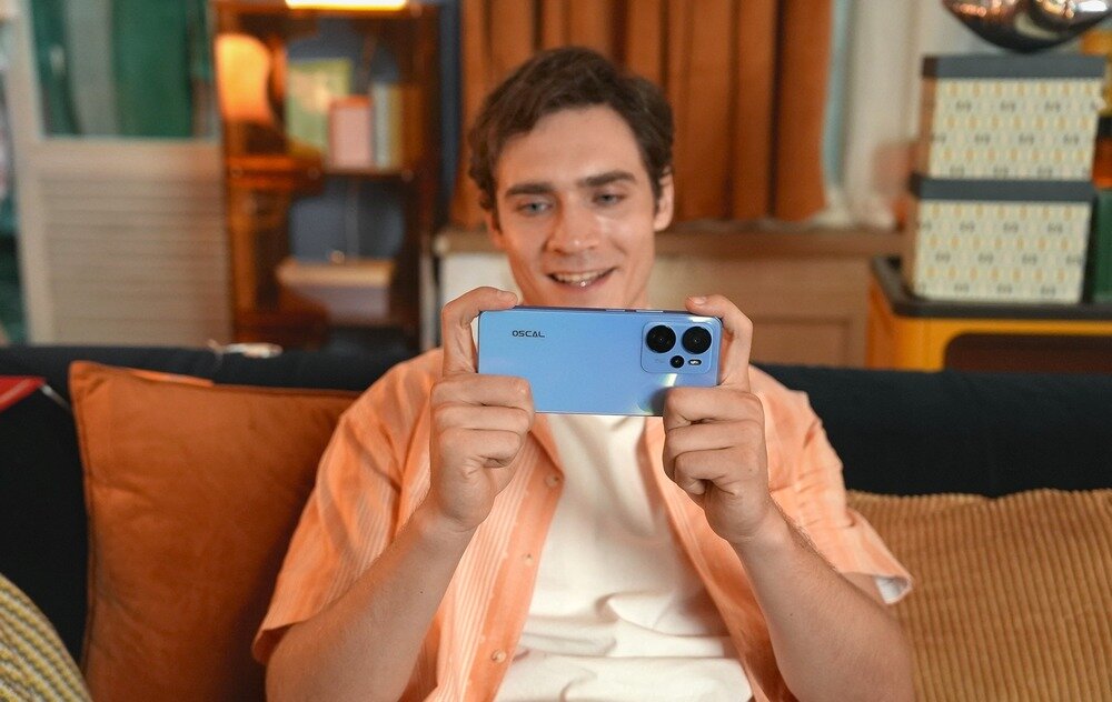 Smartfon OSCAL Tiger 13 człowiek na kanapie korzysta ze smartfona  