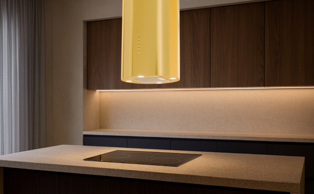 OKAP AKPO WK-4 Isla Balmera Slim Na zdjęciu widać kuchnię z czarnym, cylindrycznym okapem sufitowym zawieszonym nad blatem. W tle znajdują się jasne szafki, zlew z czarną baterią oraz dekoracje w postaci wazonu z gałązkami i butelek.