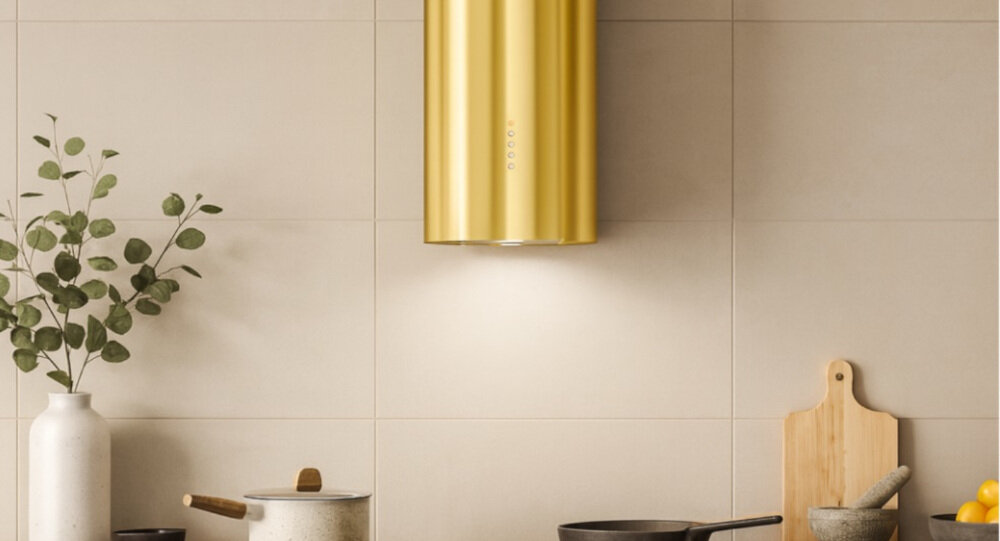 OKAP AKPO WK-12 Balmera WL Slim Na zdjęciu widać kuchnię z czarnym, cylindrycznym okapem sufitowym zawieszonym nad blatem. W tle znajdują się jasne szafki, zlew z czarną baterią oraz dekoracje w postaci wazonu z gałązkami i butelek.