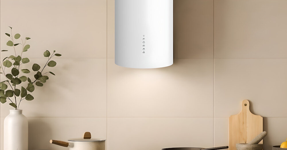 OKAP AKPO WK-4 Balmera WL Slim Nad płytą grzejną zawieszony jest biały, cylindryczny okap z panelem przycisków na froncie. Po bokach stoją wazon z gałązkami oraz drewniane akcesoria kuchenne, które ocieplają aranżację.