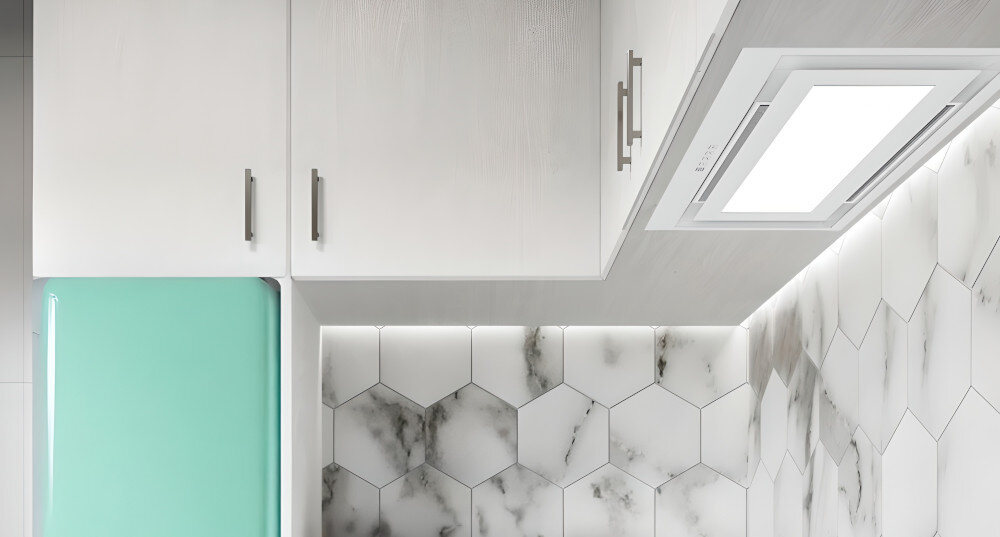 OKAP AKPO WK-12 Evita 60 Widzimy biały okap sufitowy wbudowany w podwieszany sufit nad jasną strefą kuchenną. Obok znajduje się zielona ściana z rozłożystą rośliną doniczkową, co dodaje wnętrzu świeżości.