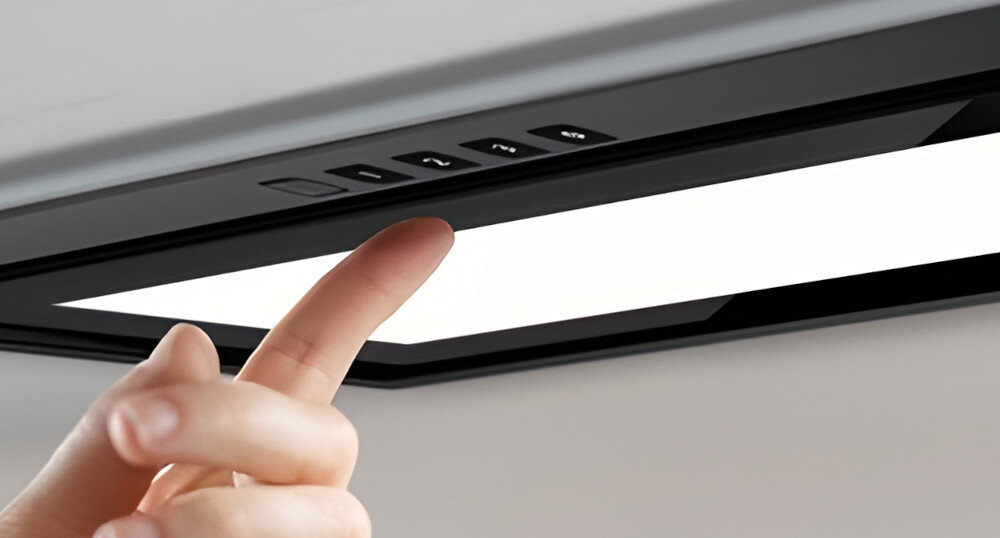 OKAP AKPO WK-12 Evita 60 Widzimy fragment czarnego okapu z widocznym wąskim wlotem powietrza oraz czterema przyciskami sterowania. Dolna płyta zasłaniająca mechanizm delikatnie odstaje, tworząc dyskretną linię podziału turbina wysoka wydajność soft-touch gesty sterowanie panel