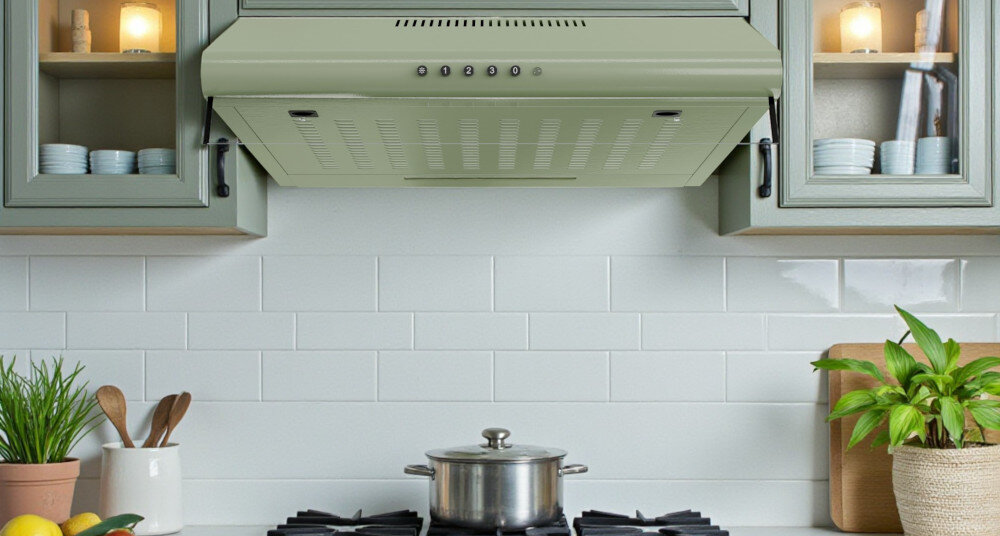 OKAP AKPO WK-7 ZK-50 Na zdjęciu znajduje się okap podszafkowy zamontowany nad płytą gazową, na tle białych, prostokątnych płytek ułożonych w cegiełkę. Po obu stronach płyty ustawiono akcesoria kuchenne, takie jak pojemnik z drewnianymi łyżkami i doniczka z rośliną, a światło z okapu równomiernie rozświetla całą strefę gotowania kolory elegancja wygląd styl