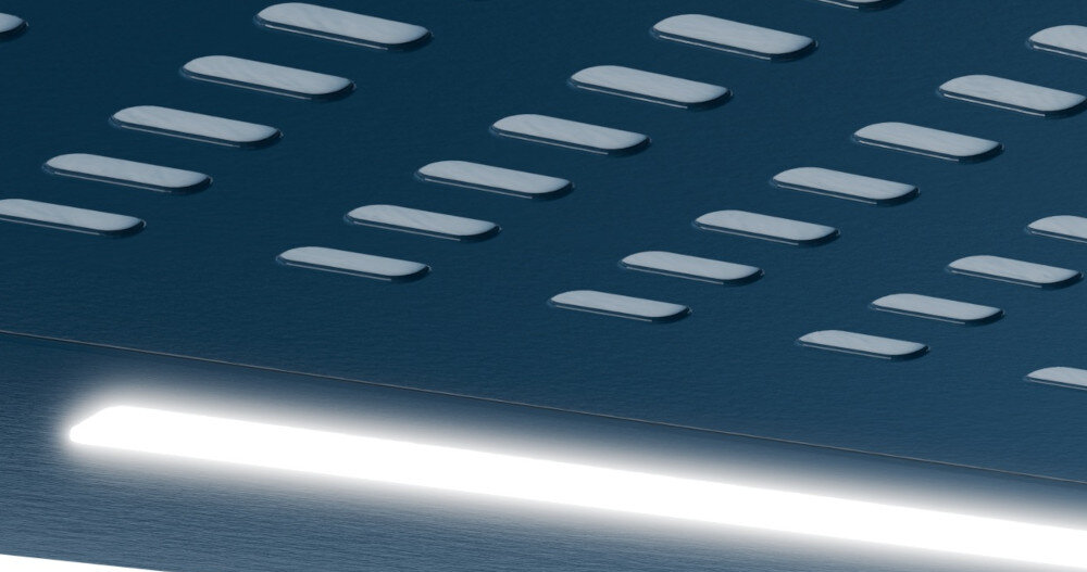 OKAP AKPO WK-7 ZK-60 Przedstawia okap podszafkowy widziany od frontu, z podłużną listwą świetlną LED w górnej części panelu oraz gęstym rzędem prostokątnych perforacji zasysających powietrze. Powierzchnia okapu jest gładka i błyszcząca, co podkreśla prostą, jednolitą formę urządzenia. światło led jasne energooszczędne oświetlenie