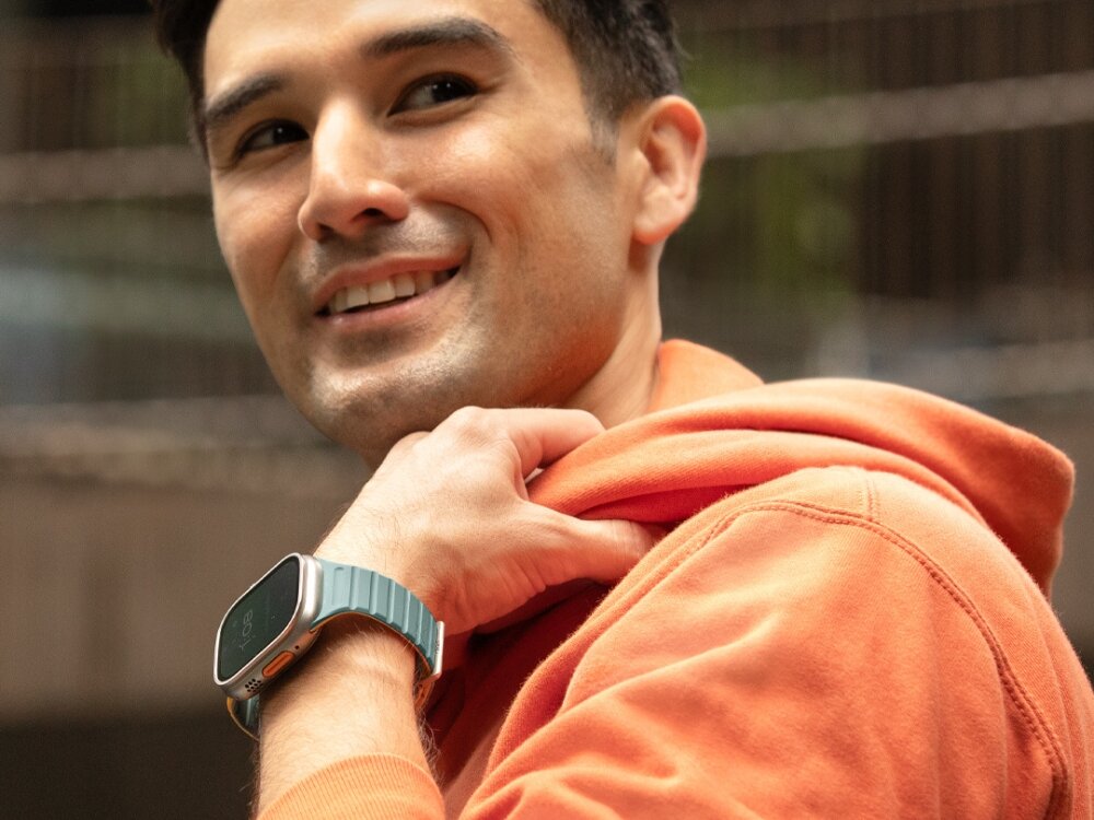 Pasek UNIQ Revix Evo do Apple Watch 1/2/3/4/5/6/7/8/9/SE/SE2/Ultra/Ultra2 (42/44/45/49 mm) Zielono-żółty, Dopasuj kolor do dnia, Mężczyzna eksponuje nadgarstek a na nim zegarek z paskiem