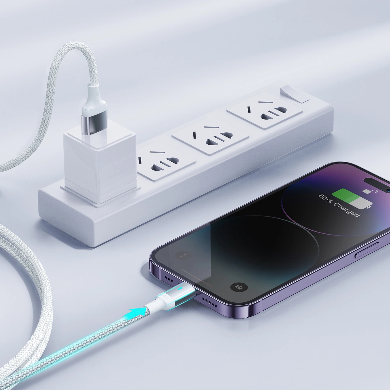 Na obrazie widać biały kabel podłączony do smartfona, który pokazuje stan naładowania baterii na poziomie 60%. Kabel jest również podłączony do białej listwy zasilającej z kilkoma gniazdami.
