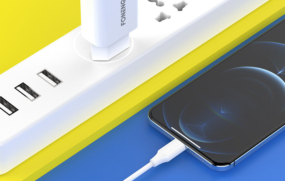 Na obrazie widać białą listwę zasilającą z kilkoma portami USB oraz podłączoną ładowarką z napisem \'FONENG\'. Obok znajduje się smartfon podłączony do ładowarki za pomocą kabla USB.