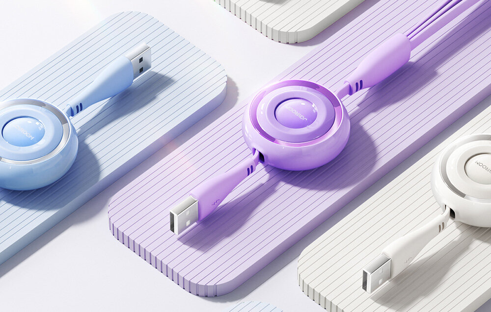 Na obrazie widoczne są kolorowe kable USB z okrągłymi obudowami, ułożone na pastelowych, prążkowanych powierzchniach. Kable mają różne kolory, w tym fioletowy i niebieski, a na obudowach widnieje napis \'JOYROOM\'.