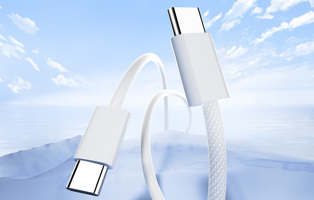 Obraz przedstawia biały kabel USB-C do USB-C z oplotem, unoszący się na tle nieba z chmurami. Kabel ma metaliczne końcówki i jest lekko zakrzywiony.