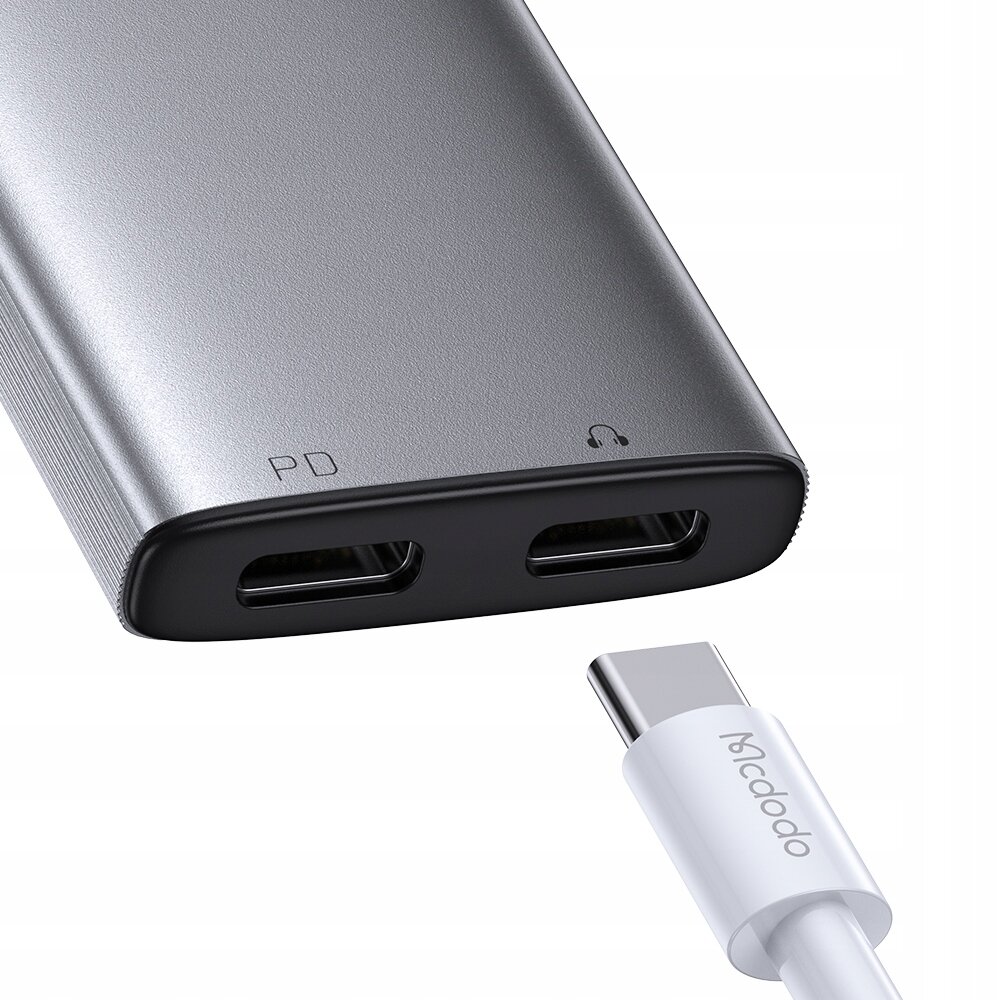 Srebrny adapter z dwoma portami USB-C oznaczonymi jako \'PD\' i symbolem słuchawek oraz biały kabel USB-C z napisem \'Mcdodo\'.