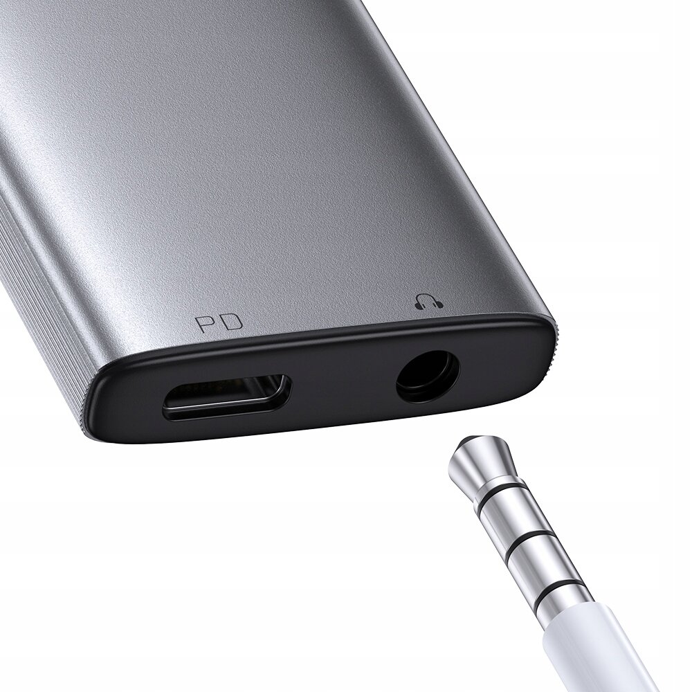 Srebrny adapter USB-C z portem mini jack 3,5 mm oraz oznaczeniami \'PD\' i ikonką słuchawek. Obok znajduje się wtyczka jack 3,5 mm.