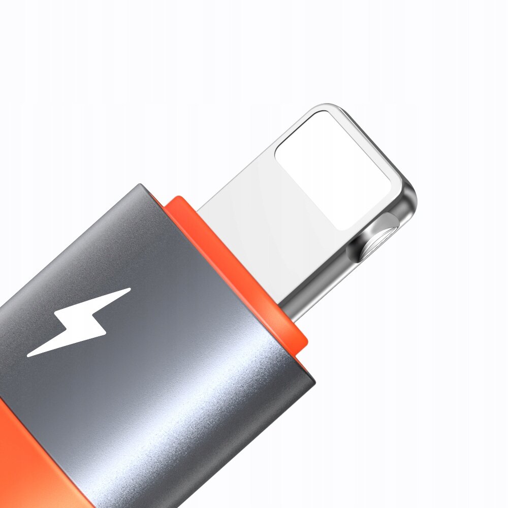 Zbliżenie na adapter z metaliczną obudową i pomarańczowym akcentem, z widocznym symbolem błyskawicy.
