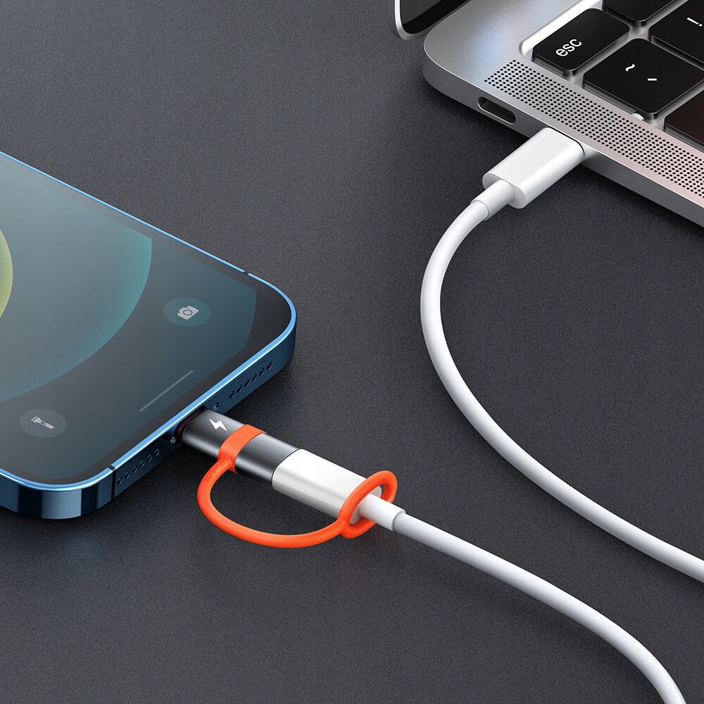 Na zdjęciu widać adapter USB-C do Lightning podłączony do niebieskiego smartfona i laptopa. Adapter ma pomarańczowy element zabezpieczający kabel.