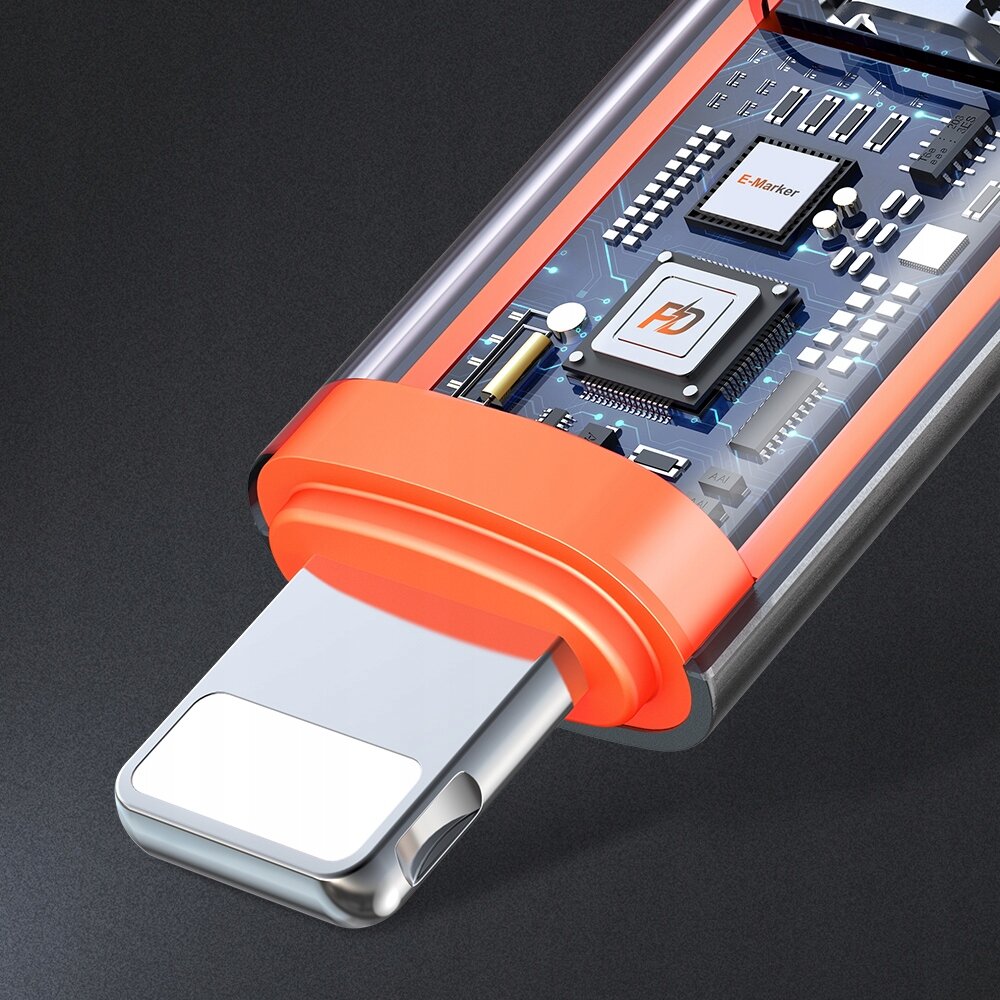 Zdjęcie przedstawia adapter USB-C do Lightning z przezroczystą obudową, ukazującą wewnętrzne komponenty elektroniczne z widocznymi napisami \'E-Marker\' i \'PD\'. Adapter ma pomarańczowy element ochronny wokół złącza.