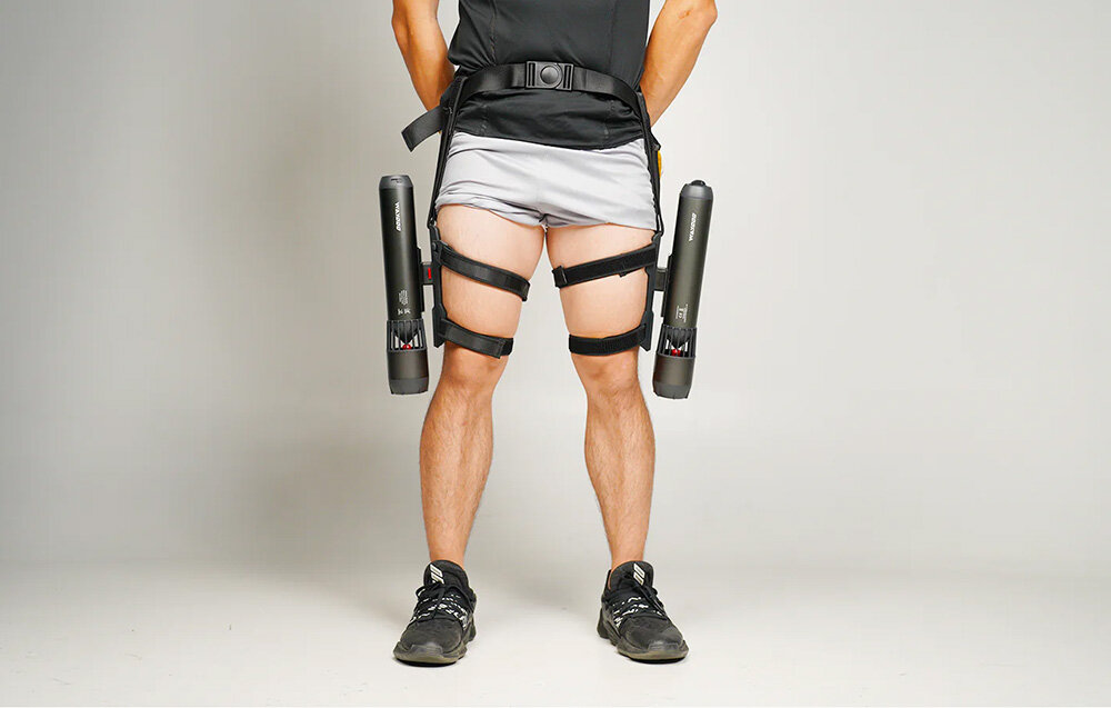 Mocowanie na nogę do skutera podwodnego WAYDOO 4010000039 jasne tło osoba stoi na podłodze z przymocowanymi do nóg skuterami wodnymi mocowanie komfort nurkowanie prędkość