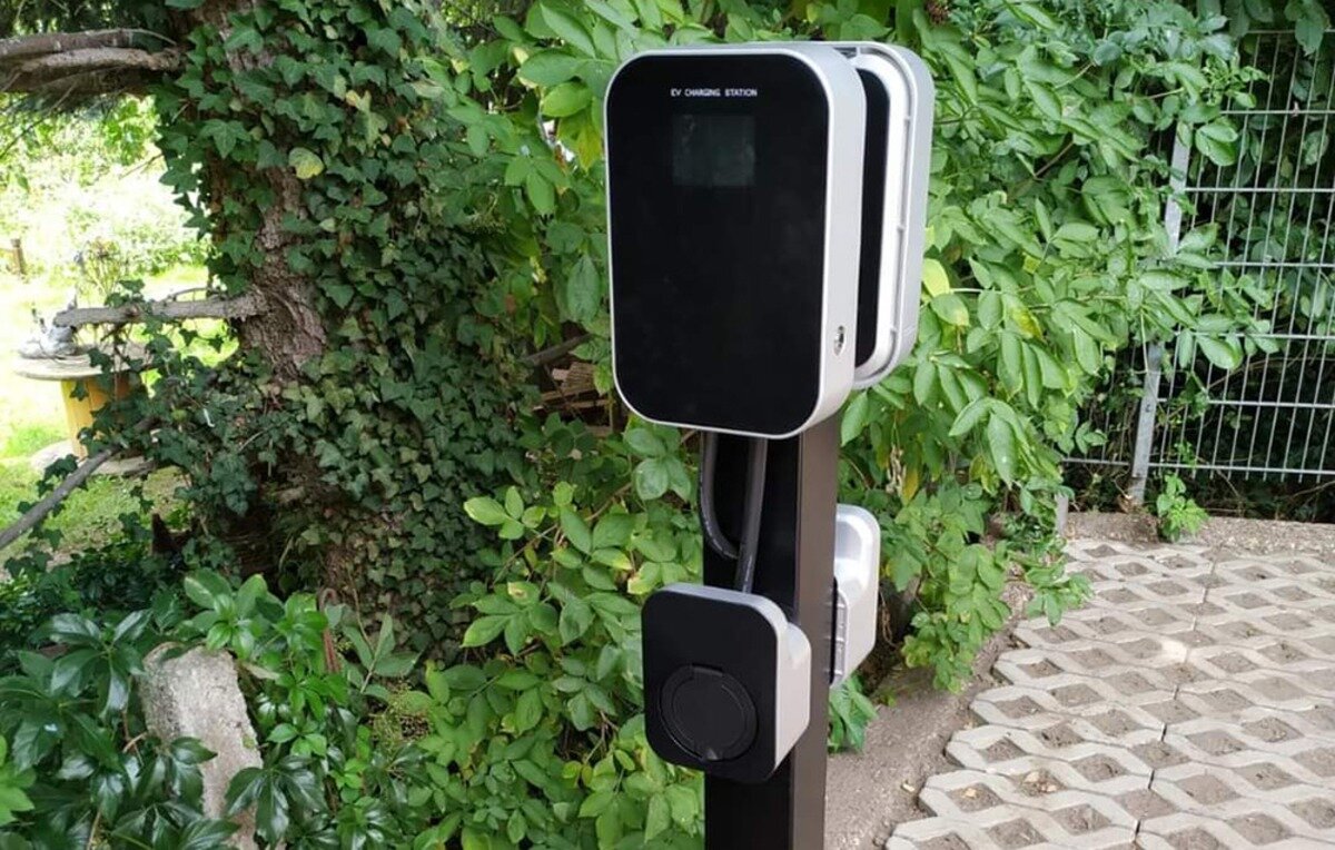 Ładowarka do samochodu elektrycznego BESEN BS20 App 22 kW Stacja ładowania pojazdów elektrycznych zamontowana na słupku na tle zieleni.