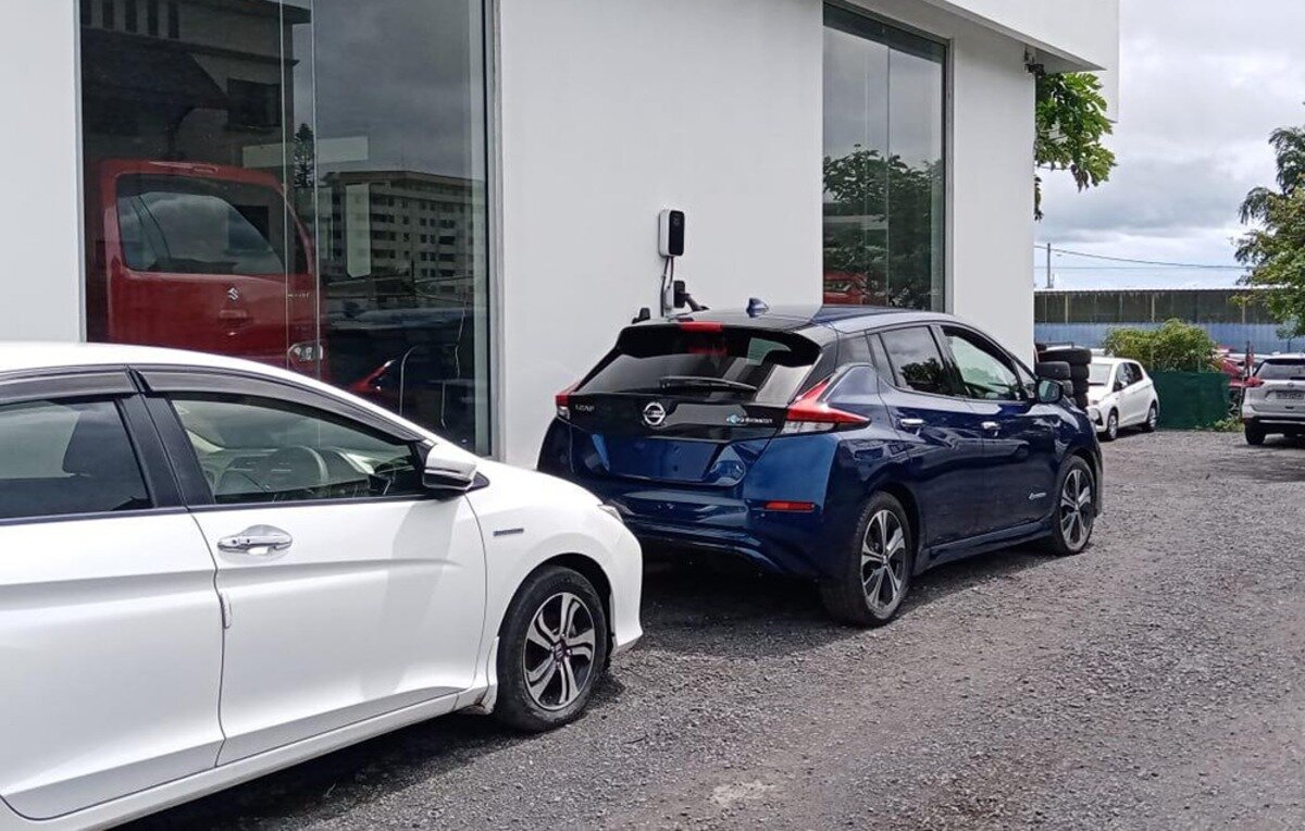 Ładowarka do samochodu elektrycznego BESEN BS20 Typ A 22 kW Granatowy Nissan Leaf podłączony do ładowarki samochodowej na parkingu przed białym budynkiem.