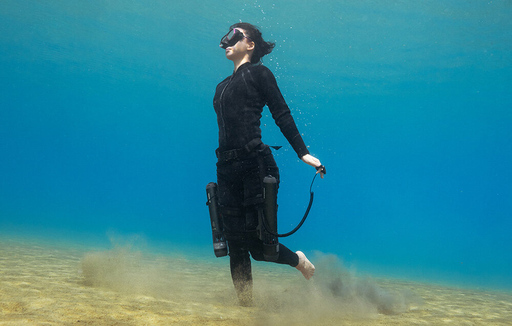 Kontroler na palec do skutera podwodnego WAYDOO 4010000053 akwen wodny nurek zbliżenie na nogi nurka nurek w dłoni trzyma kontroler na nogach ma przymocowane napędy skutera wodnego materiały przystosowane do pracy w środowisku wodnym montaż przebiega sprawnie i nie wymaga skomplikowanych czynności solidna budowa
