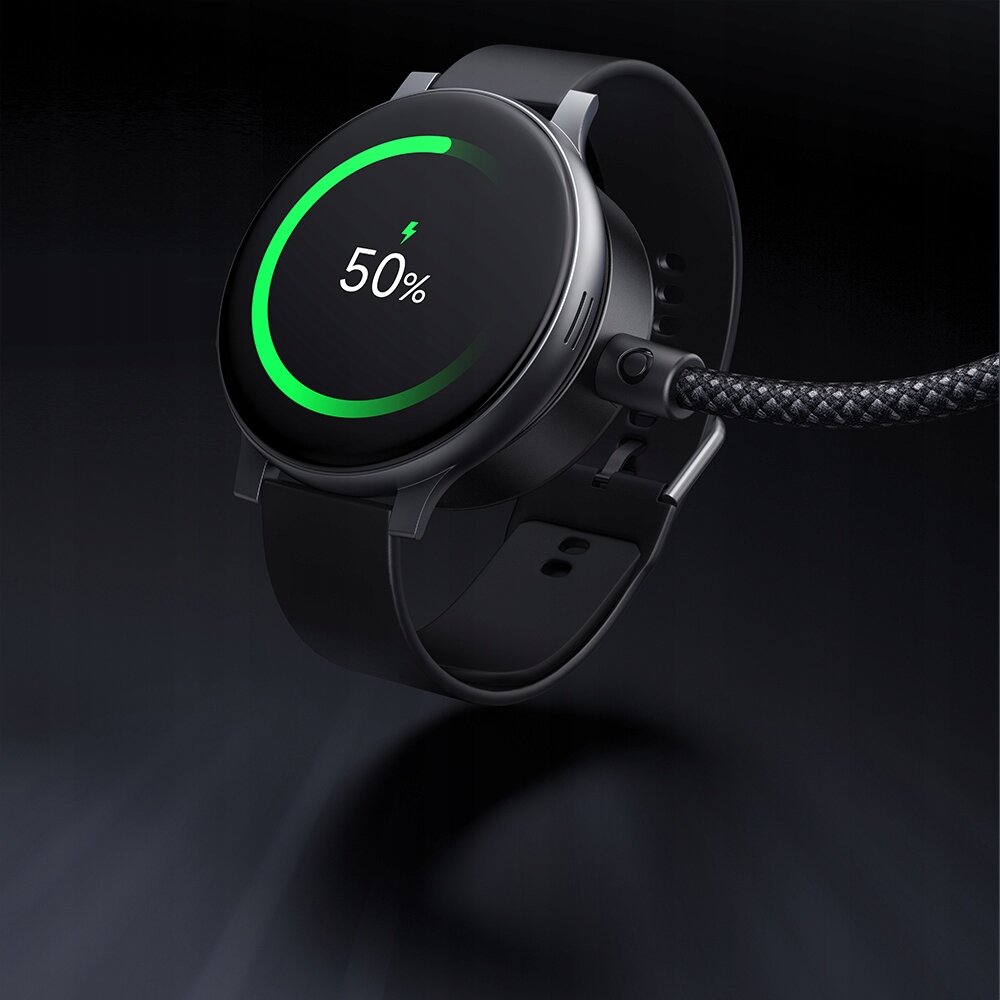 Czarny smartwatch z okrągłym wyświetlaczem pokazuje 50% naładowania baterii z zielonym okręgiem wokół. Urządzenie jest podłączone do plecionego kabla USB-C.