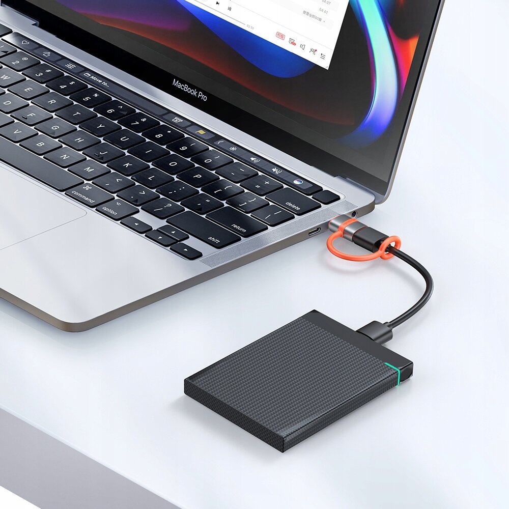 Na obrazie widać laptop z podłączonym kablem USB do zewnętrznego dysku twardego. Na ekranie laptopa wyświetlony jest interfejs programu z kolorowymi elementami.