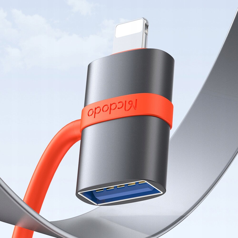 Na obrazie widoczny jest adapter z metaliczną obudową i czerwonym kablem, z logo \'mcdodo\'. Adapter posiada złącze USB-A oraz Lightning.