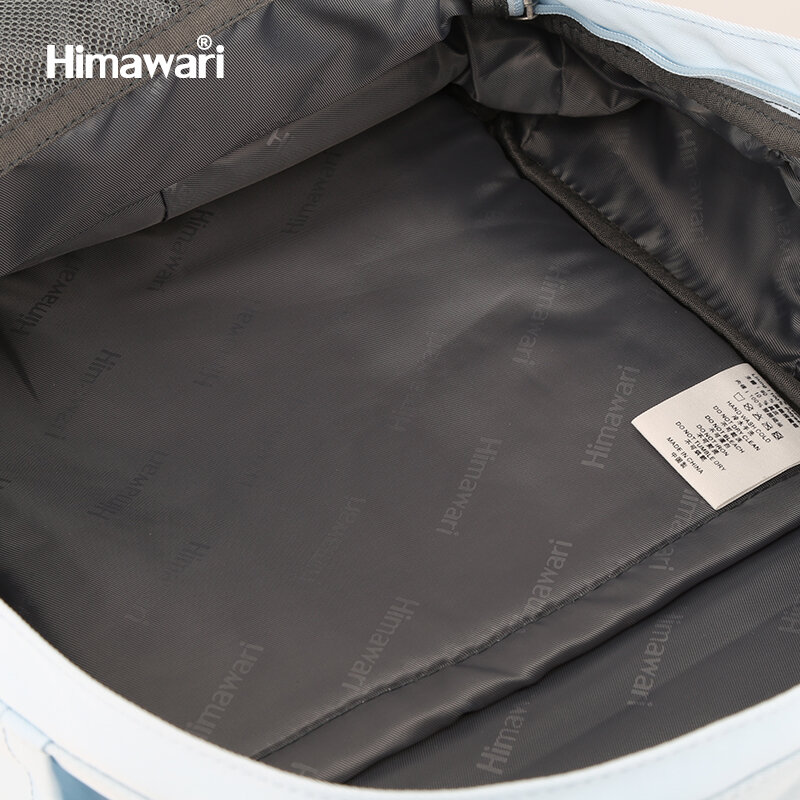 Wnętrze plecaka z szarym materiałem, na którym widnieje powtarzający się napis \'Himawari\'. Widoczna jest również metka z tekstem w kilku językach.
