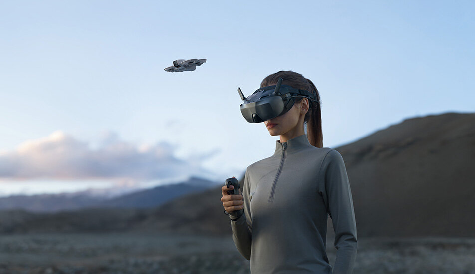 Kobieta używająca DJI Goggles N3 na dworze, w tle widać drona DJI.