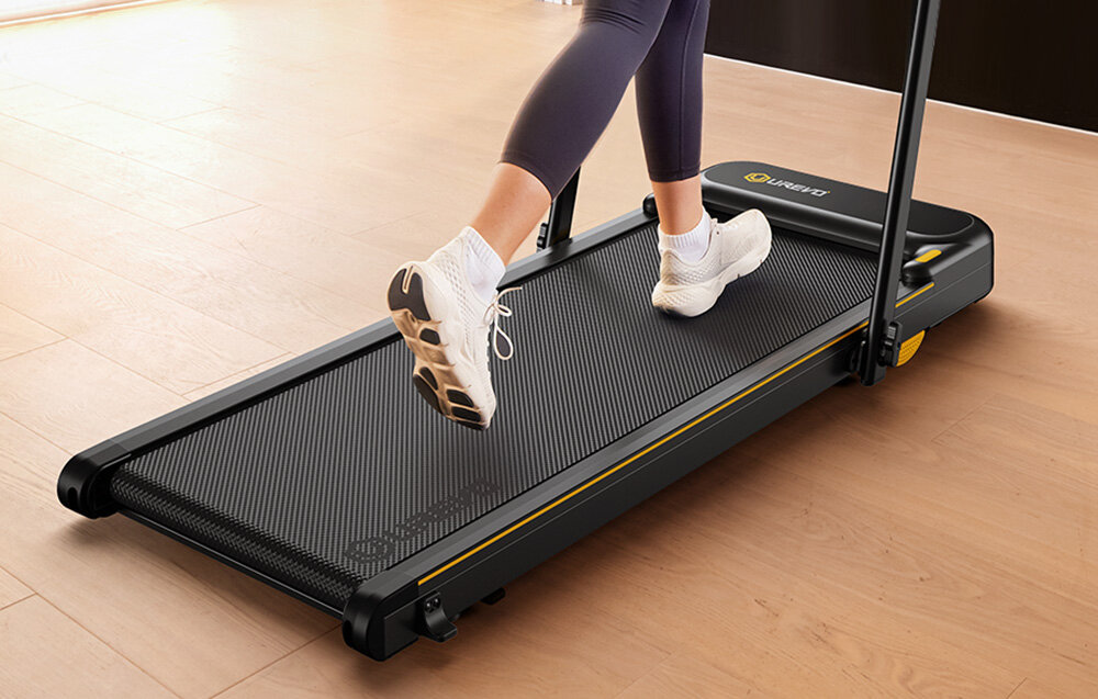 Bieżnia elektryczna UREVO Strol 2E Smart 2w1 550W 10km-h pokój osoba korzysta z bieżni zbliżenie na pas biegowy inteligentna bieżnia domowa kompatybilność z aplikacjami Zwift, Kinomap i UREVO integracja z ekosystemem Xiaomi moduł Bluetooth