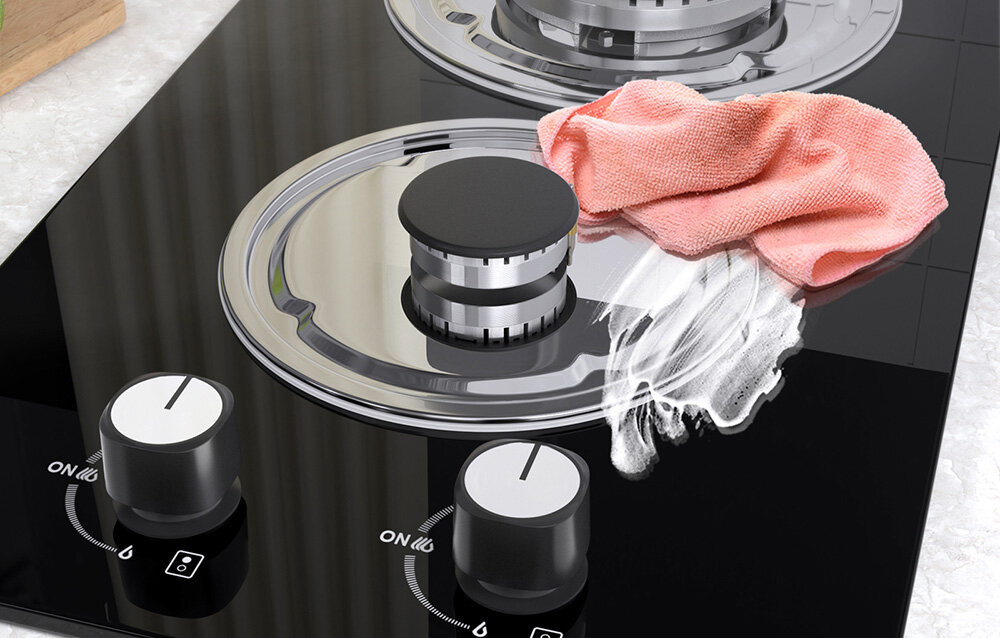 PŁYTA GAZOWA ISEASY MGBG-312A Na płycie gazowej widać środki czyszczące rozprowadzone ściereczką, co ukazuje proces pielęgnacji powierzchni. Metalowe elementy palnika tworzą kontrast z czarnym szkłem regulacja płomienia antypoślizgowe pokrętła łatwe czyszczenie szklana płyta szybka pielęgnacja