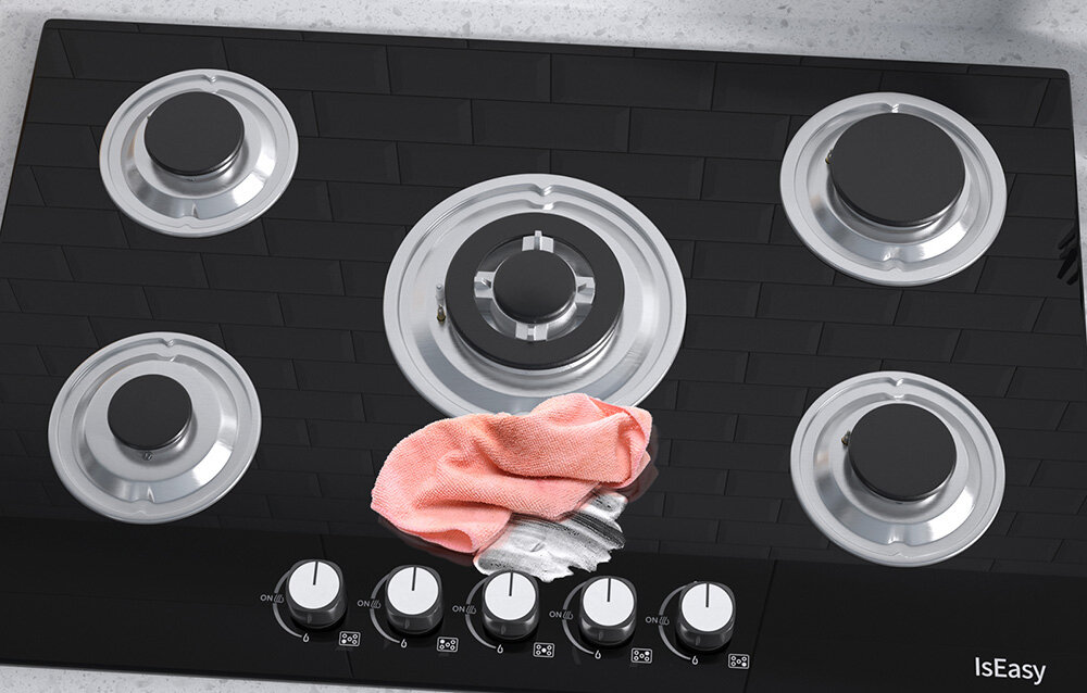 Płyta gazowa ISEASY MGBG-775 Szklana powierzchnia płyty została częściowo przetarta miękką ściereczką, co uwidacznia jej gładkie wykończenie. Widoczne są także metalowe elementy palników w pełnym układzie pięciu miejsc szklana powierzchnia łatwe czyszczenie gładka płyta estetyczny wygląd