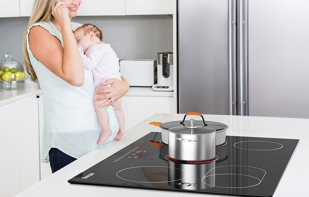 Płyta ceramiczna ISEASY LT5-04 Kobieta trzyma dziecko na rękach, a na płycie obok niej gotuje się potrawa w srebrnym garnku. Widać również kilka rozgrzanych pól grzewczych o różnych wielkościach cicha praca system chłodzenia płyta