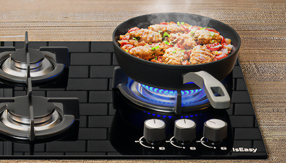 Płyta gazowa ISEASY MGBG-603 Na płycie gazowej stoi patelnia z gotującym się daniem, podgrzewana równym, niebieskim płomieniem. Czarny panel odbija otoczenie, a metalowe ruszty stabilnie podtrzymują naczynie intuicyjna obsługa ergonomiczne pokrętła szybki montaż płyta do zabudowy instrukcja montażu