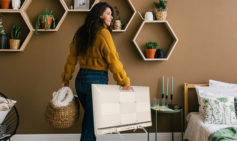 Telewizor METZ 32MTE7000Z niska waga przenośny, osoba trzymająca telewizor za uchwyt