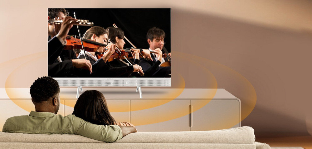 Telewizor METZ 32MTE7000Z Dolby Audio dźwięk przestrzenny, telewizor stojący na komkodzie, rodzina ogladająca film siedząca na kanapie