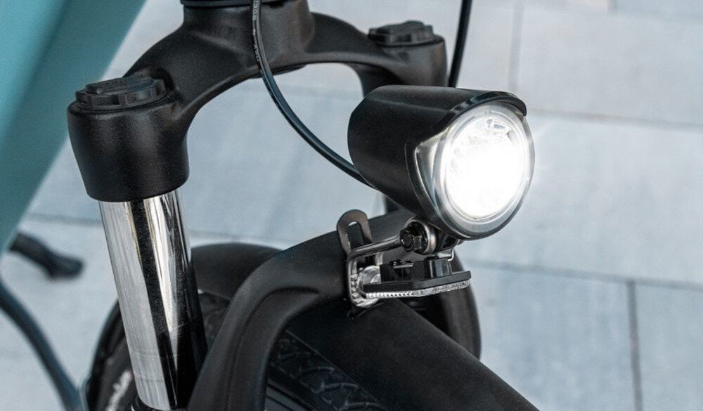 Rower elektryczny CECOTEC Urban Pro M18 28 cali Niebieski chodnik zbliżenie na przednie światło przednie i tylne oświetlenie LED bezpieczeństwo jasne światło przednie widoczność drogi po zmroku tylne sygnalizuje Twoją obecność innym uczestnikom ruchu technologia LED lampki zużywają mniej energii i pracują dłużej wymagane przez prawo drogowe