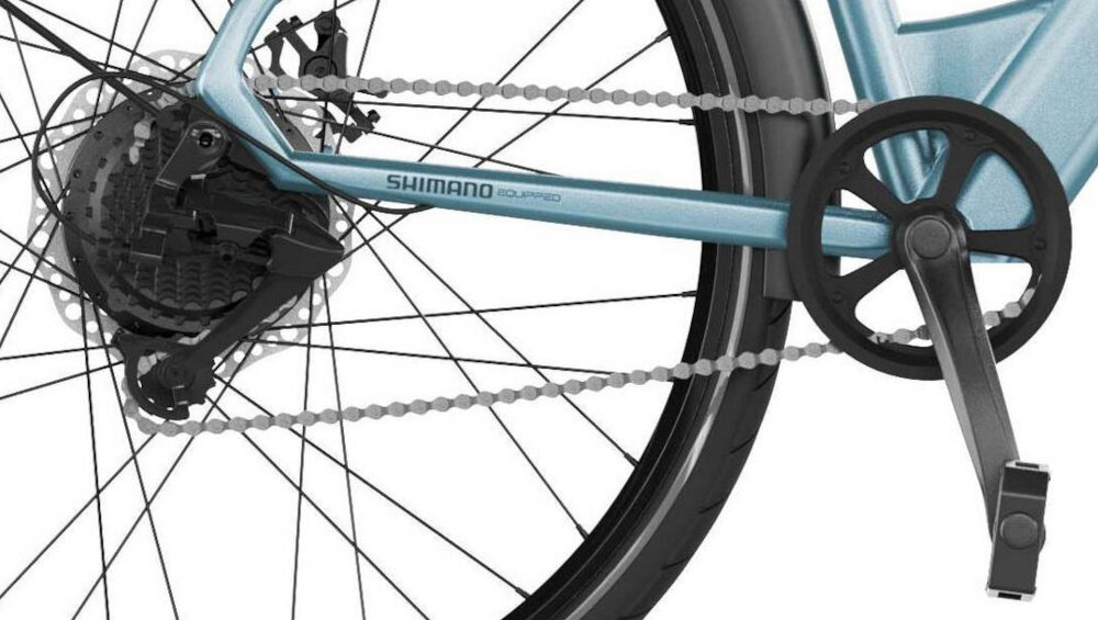 Rower elektryczny CECOTEC Urban Pro M18 28 cali Niebieski białe tło zbliżenie na korbę i wolnobieg lekka i aluminiowa konstrukcja korby marki SHIMANO wolnobieg SHIMANO typu AMFTZ5007428 solidny wytrzyma obciążenie nawet w trudnych warunkach wytrzyma bardzo duży nacisk na pedały