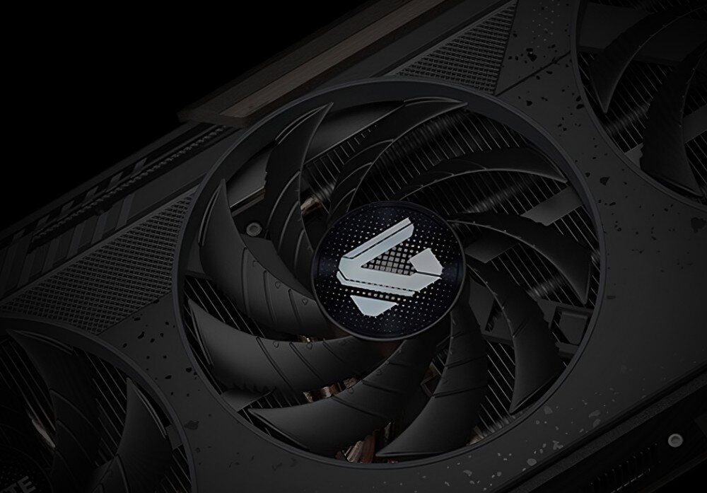 Karta graficzna GIGABYTE Radeon RX 9060XT GAMING 8G OC Zbliżenie na środkowy wentylator karty graficznej z logo w kształcie stylizowanej litery 'G' na czarnym tle, chłodzenie, wentylatory, radiator