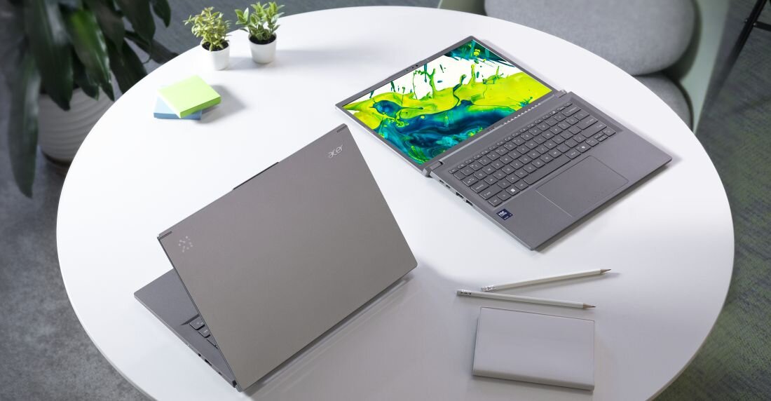 Dwa laptopy Acer Aspire 14 AI na okrągłym białym stole – jeden zamknięty, drugi otwarty z ekranem rozłożonym na płasko (zawias 180 stopni), widoczne elegancki wzornictwo i smukła obudowa