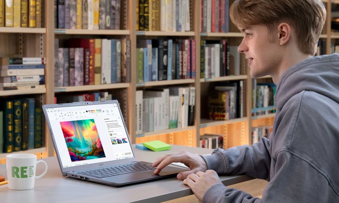 Osoba pracująca na laptopie Acer Aspire 14 AI w bibliotece, na ekranie kreator grafiki AI, na biurku kubek i karteczki, w tle regały z książkami – ultrabook z portem Thunderbolt 4 do pracy kreatywnej  