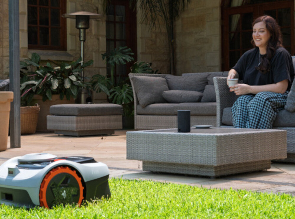 Robot koszący SEGWAY Navimow i105E robot na trawie w tle dom osoba siedzi na fotelu ogrodowym wbudowana kamera z inteligencją AI i kątem widzenia 140° rozpoznaje ponad 150 typów obiektów porusza się płynnie
